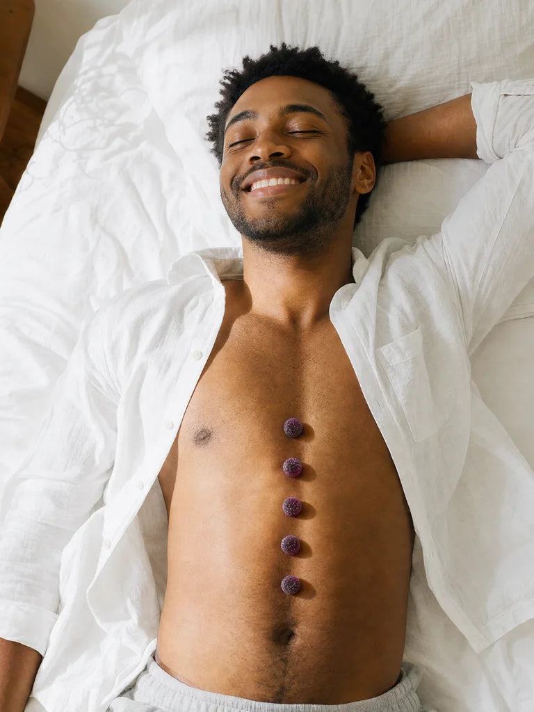 A relaxed man lying on a bed with Loosen Up gummies lined down his torso